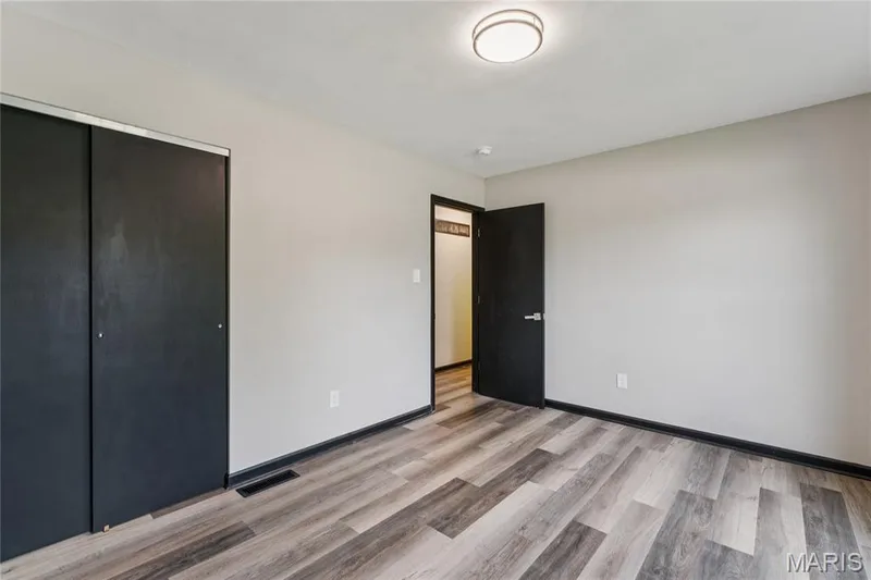 Wood-finish flooring, dark trim throughout, a flush-mount ceiling light fixture, and a dark sliding closet door — 2801 Droste Road, St Charles, MO 63301