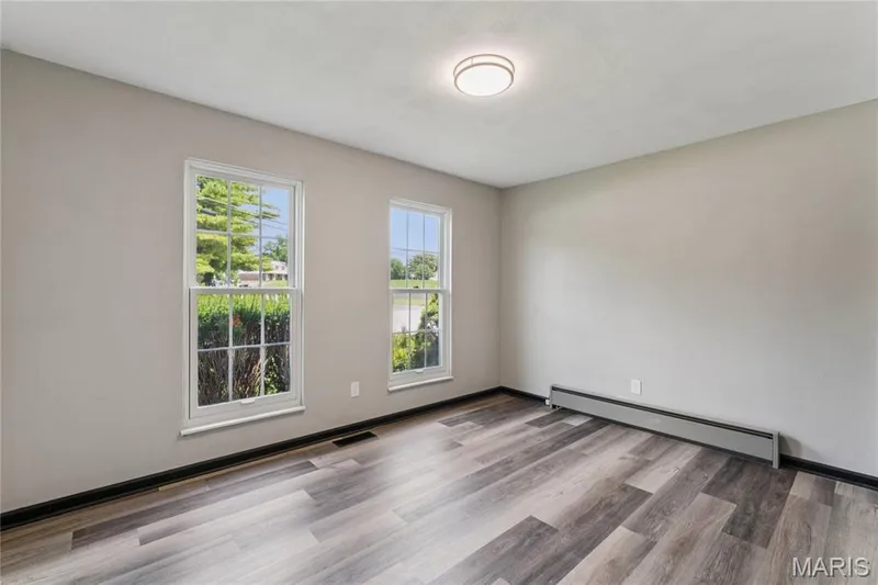 Recessed ceiling light, grey painted walls, wood-finish flooring, two double-hung windows, and a baseboard heating unit — 2801 Droste Road, St Charles, MO 63301