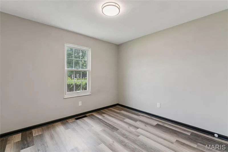 Neutral wall paint, wood-finish flooring, white window trim, and a flush-mount ceiling light — 2801 Droste Road, St Charles, MO 63301