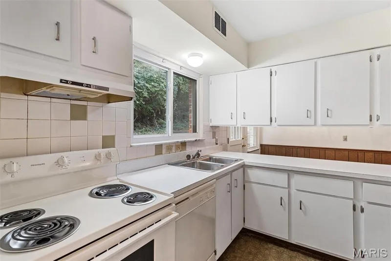 White cabinetry with chrome hardware, white countertops, stainless steel double basin sink, white tile backsplash, and a window above the sink — 1192 Cantina Drive, Chesterfield, MO 63141