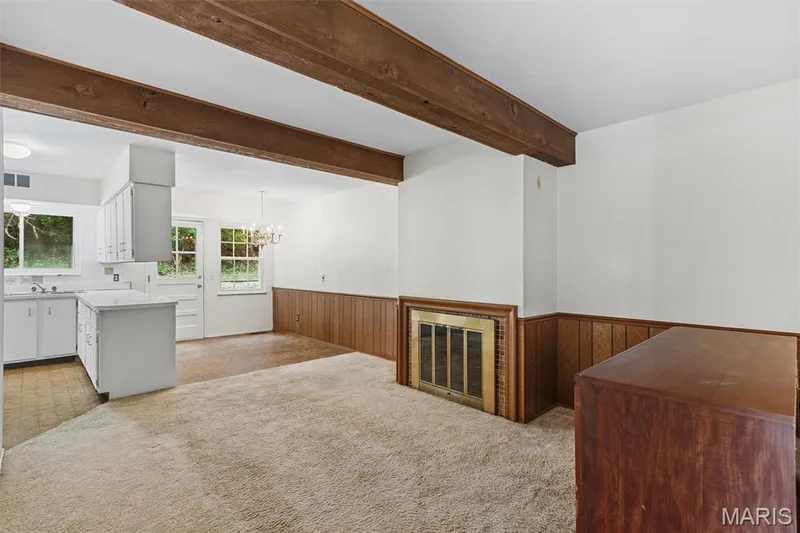 Kitchen and breakfast room open to nice family room/hearth room with exposed wood beams, integrated kitchen with white cabinetry, built-in fireplace, and wood paneling — 1192 Cantina Drive, Chesterfield, MO 63141