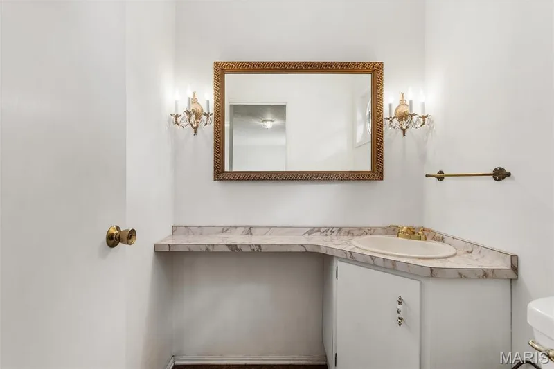 Half bath on main level is perfect for guests and features built-in vanity with a marble-finish countertop, integrated sink, and cabinet storage — 1192 Cantina Drive, Chesterfield, MO 63141