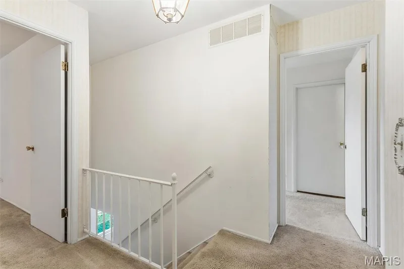Decorative stairway with carpeted flooring, white walls, and a white stair railing with a decorative finial — 1192 Cantina Drive, Chesterfield, MO 63141