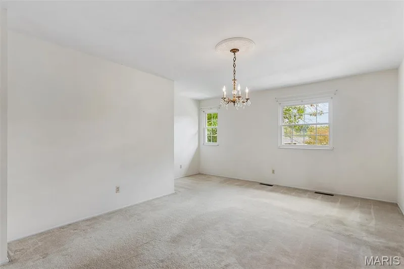 Sizable primary bedroom has large walk-in closet, en-suite bath and features neutral wall color with two windows, a chandelier, and carpet flooring — 1192 Cantina Drive, Chesterfield, MO 63141