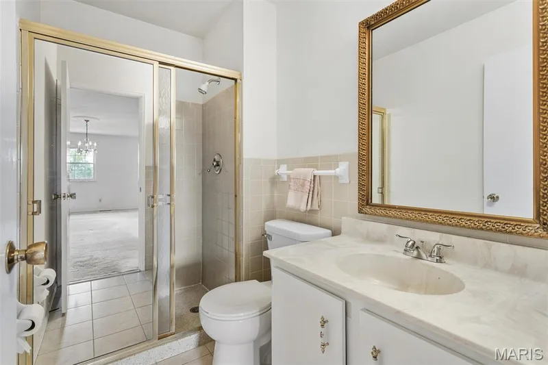 Primary bathroom with a large vanity, integrated sink, ceramic tile flooring, tile surround, and gold-framed mirror — 1192 Cantina Drive, Chesterfield, MO 63141