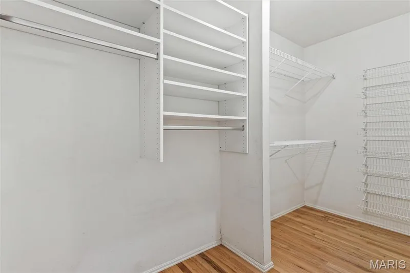 Large walk-in closet in primary bedroom with built-in shelving, hanging rods, wire shoe rack shelving, and hardwood flooring — 1192 Cantina Drive, Chesterfield, MO 63141