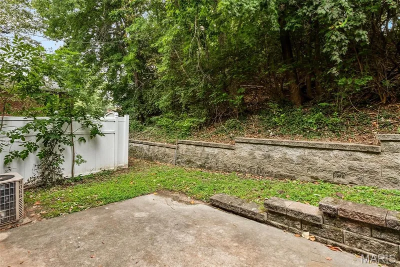 Outdoor concrete patio with a privacy fence and stone retaining walls — 1192 Cantina Drive, Chesterfield, MO 63141