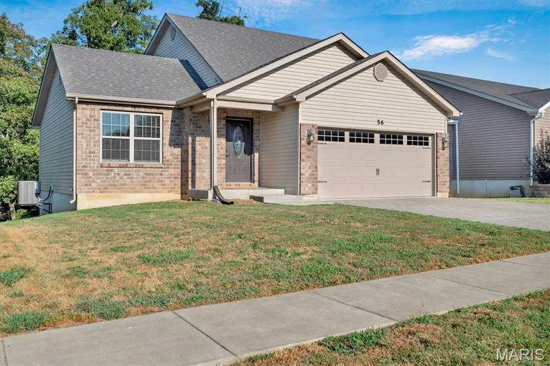 Brick and siding exterior featuring an attached two-car garage, a covered entry, and a concrete driveway — 56 Huntleigh Park Court, Wentzville, MO 63385