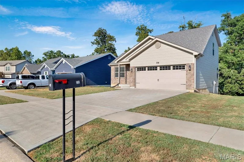 Attached two-car garage, brick facade accents, vinyl siding exterior, concrete driveway, and mature perimeter trees — 56 Huntleigh Park Court, Wentzville, MO 63385