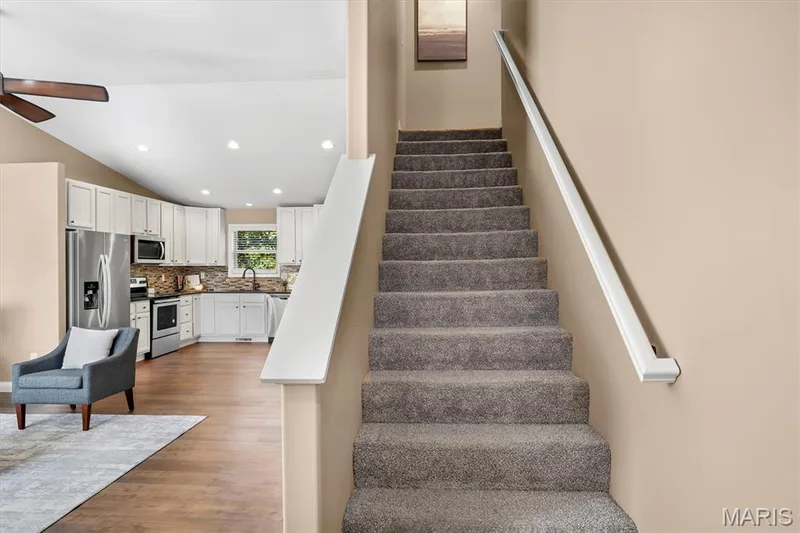 Carpeted staircase with white handrail — 56 Huntleigh Park Court, Wentzville, MO 63385