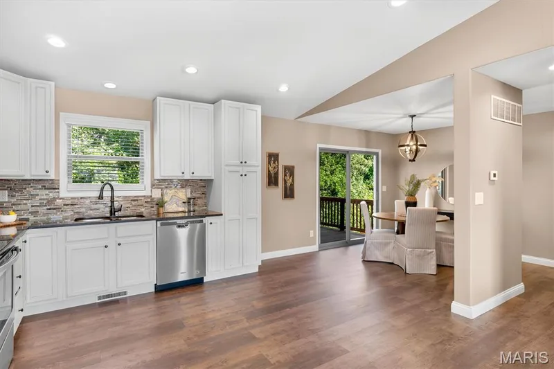 Kitchen with white cabinetry, dark countertops, and a mosaic tile backsplash — 56 Huntleigh Park Court, Wentzville, MO 63385