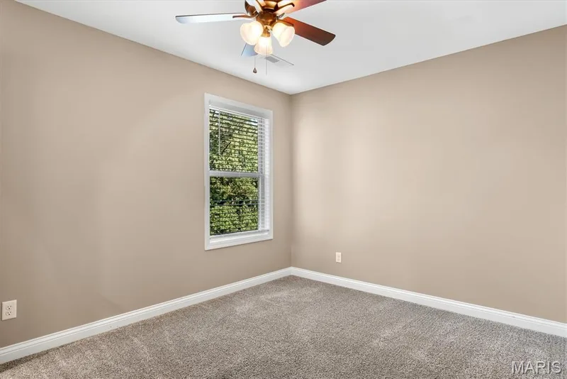 Soft neutral wall paint, plush carpeting, white window trim, and a ceiling fan with integrated lighting — 56 Huntleigh Park Court, Wentzville, MO 63385
