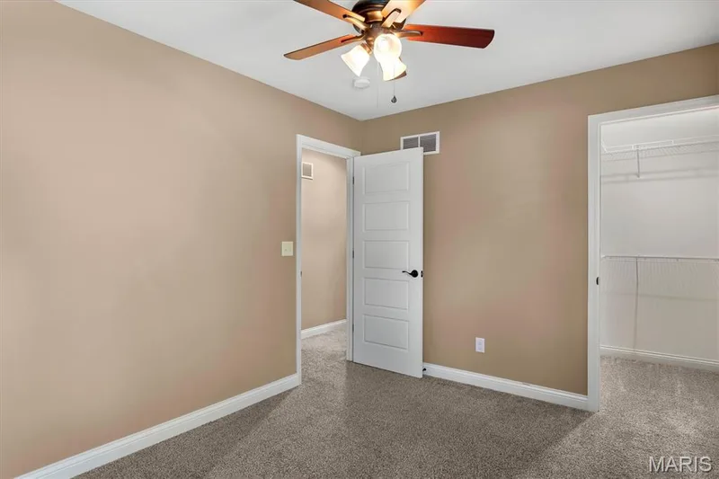 Textured carpet flooring, ceiling fan with integrated lighting, white trim, and a built-in closet with wire shelving — 56 Huntleigh Park Court, Wentzville, MO 63385
