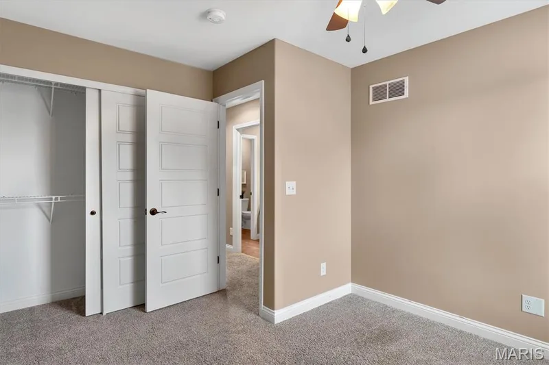 Plush gray carpet flooring, a ceiling fan with light fixture, and neutral wall paint — 56 Huntleigh Park Court, Wentzville, MO 63385