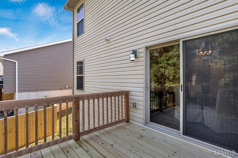 Wood deck with natural finish, wood railing, sliding glass door, exterior wall lighting fixture, and horizontal siding — 56 Huntleigh Park Court, Wentzville, MO 63385