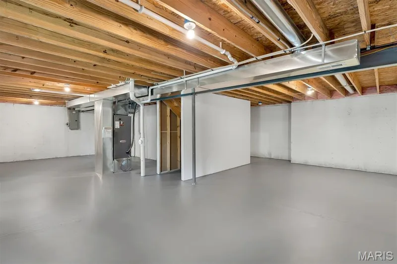 Unfinished basement with a painted concrete floor, exposed wood ceiling joists, and integrated overhead lighting — 56 Huntleigh Park Court, Wentzville, MO 63385