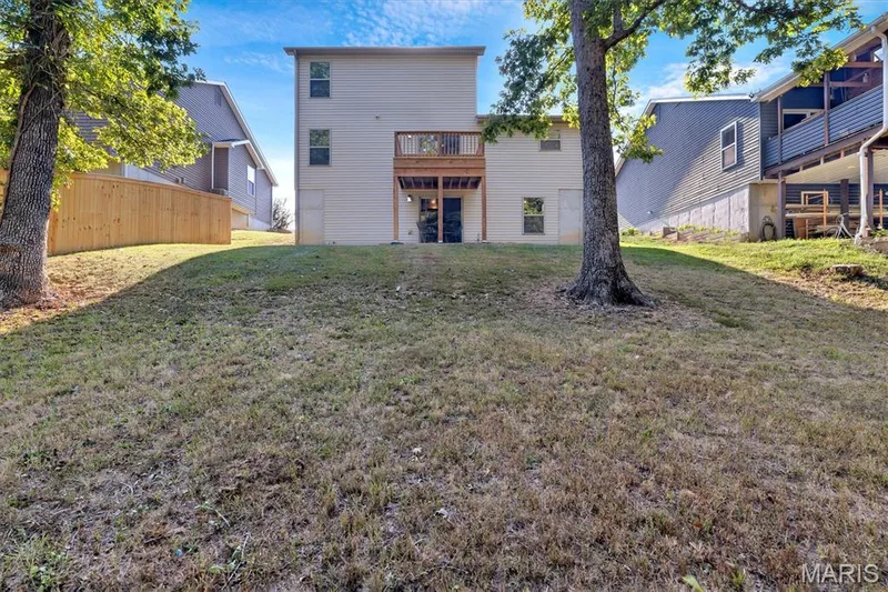 Rear exterior with a wooden deck, a lower-level patio, and a sloped lawn — 56 Huntleigh Park Court, Wentzville, MO 63385