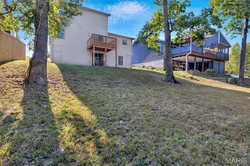Rear exterior with siding, upper-level deck, lower-level patio, and sliding glass door access — 56 Huntleigh Park Court, Wentzville, MO 63385