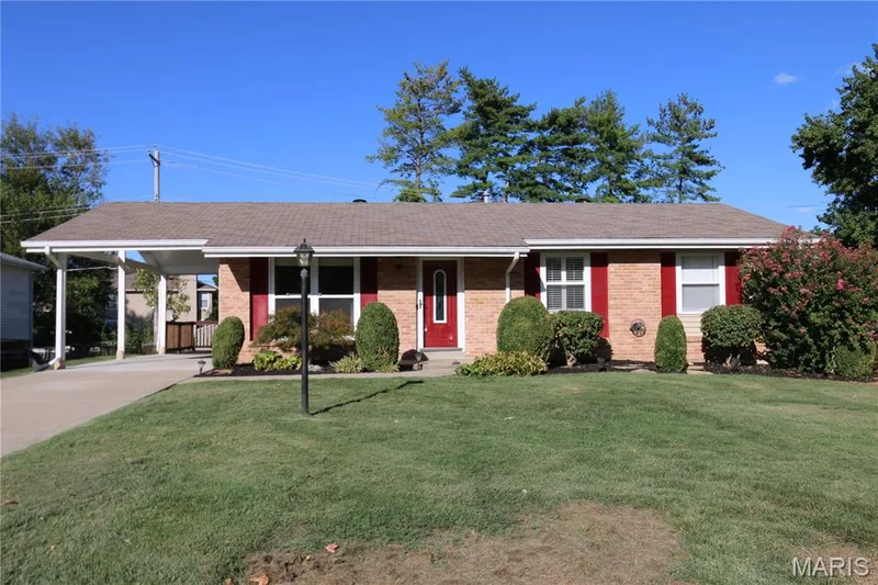 Brick exterior with red shutters, asphalt shingle roof, attached carport, concrete driveway, and front lawn — 3 Oxbow Road, St Peters, MO 63376