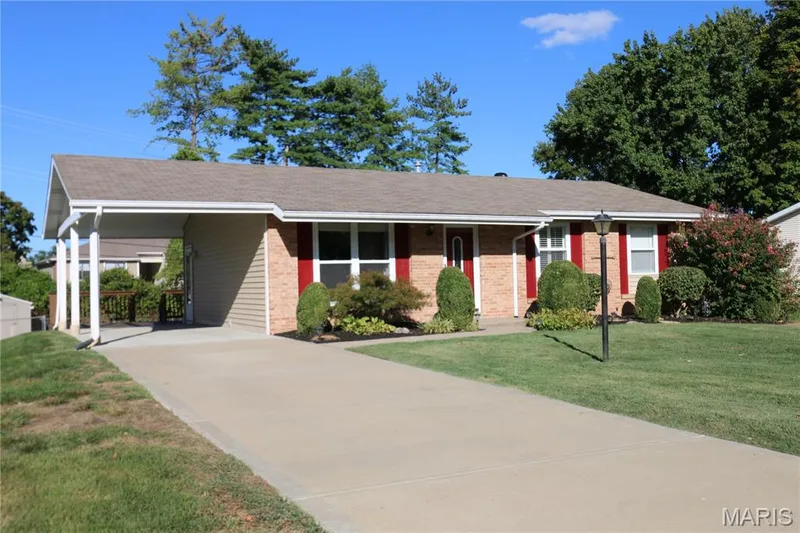 Brick facade with red shutters, attached carport, concrete driveway, and established front landscaping — 3 Oxbow Road, St Peters, MO 63376