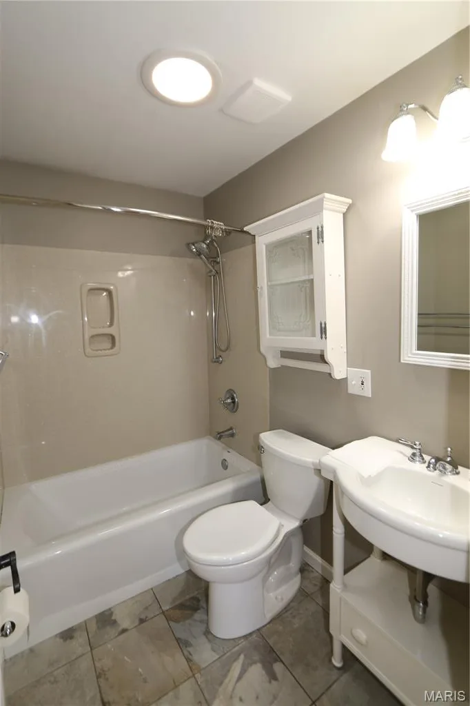 HALL FULL_BATH - White porcelain bathtub with a built-in shower, wall-mounted vanity with an integrated sink, and a mirrored medicine cabinet. PLUS, there is a tube light in the ceiling that seems to glow at night with the moonlight. — 3 Oxbow Road, St Peters, MO 63376