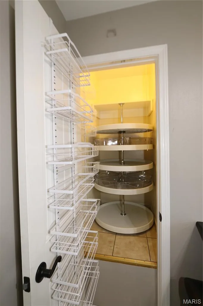Pantry with multi-level rotating shelves, door-mounted storage racks, and tile flooring — 3 Oxbow Road, St Peters, MO 63376