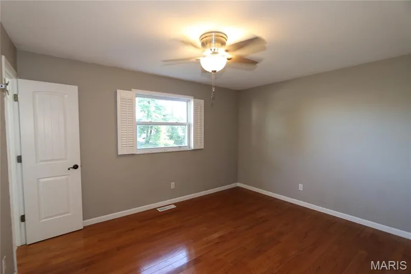 Shutters open to the sides. Wood-finish flooring, neutral wall color, ceiling fan with integrated lighting, white interior door, and white window shutters — 3 Oxbow Road, St Peters, MO 63376