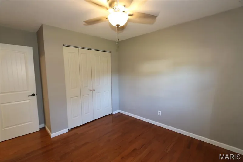 #2 Bedroom - View from corner. Wood-finish flooring with white trim, light gray walls, and a ceiling fan with integrated lighting — 3 Oxbow Road, St Peters, MO 63376