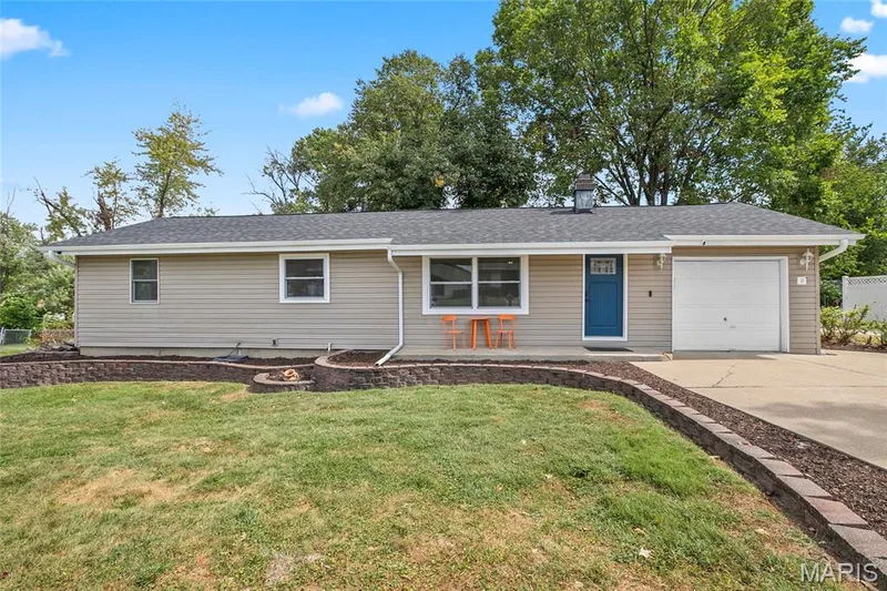 Tan siding exterior with a single-car garage and a blue entry door — 712 Highland Drive, O'Fallon, MO 63366