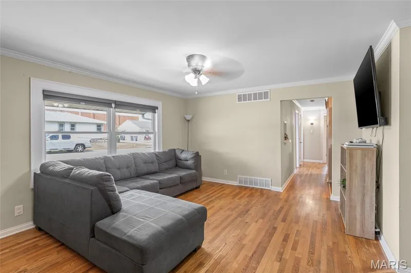 Hardwood flooring, crown molding, ceiling fan with integrated lighting, and white trim — 712 Highland Drive, O'Fallon, MO 63366