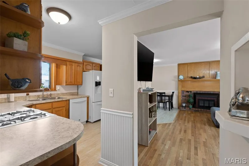 Kitchen featuring wood cabinetry, white appliances, and a gas cooktop — 712 Highland Drive, O'Fallon, MO 63366