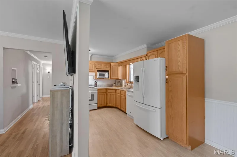 Kitchen featuring wood-finish cabinetry, white appliances, and light countertops — 712 Highland Drive, O'Fallon, MO 63366