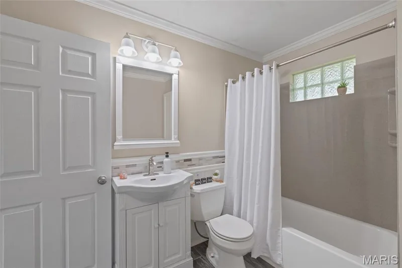 White panel door, vanity with integrated sink, chrome faucet, wall-mounted light fixture, glass block window — 712 Highland Drive, O'Fallon, MO 63366
