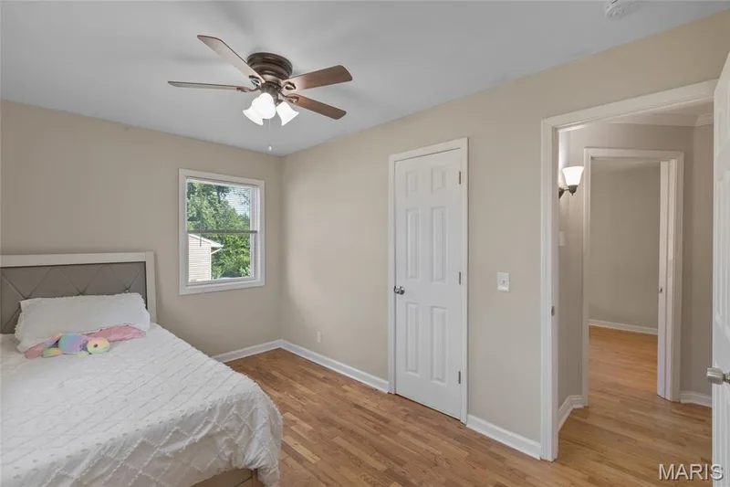 Wood-finish flooring, ceiling fan with integrated lighting, white trim, and a white six-panel door — 712 Highland Drive, O'Fallon, MO 63366