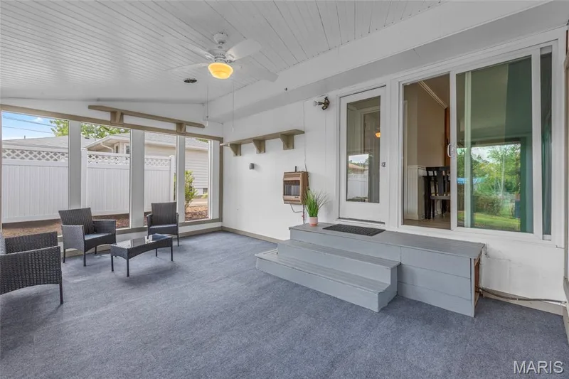 Enclosed patio featuring a beadboard ceiling with a ceiling fan, multiple windows, a sliding glass door, and exterior steps — 712 Highland Drive, O'Fallon, MO 63366