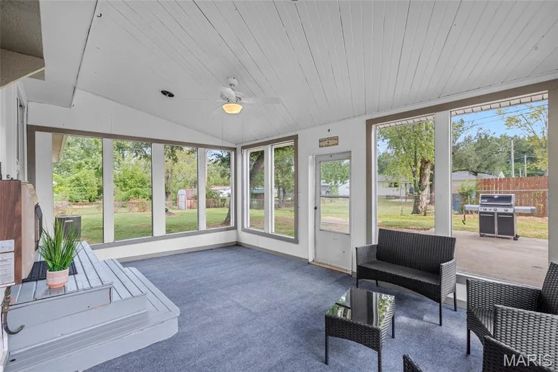 Enclosed porch with sloped ceiling, beadboard ceiling panels, ceiling fan with integrated lighting, and multiple windows — 712 Highland Drive, O'Fallon, MO 63366