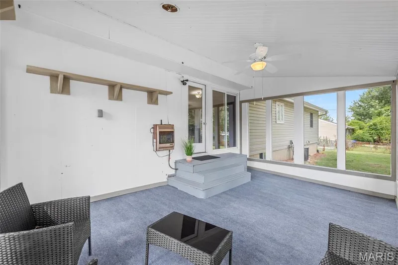 Covered outdoor patio with a corrugated ceiling, light blue carpeting, and a ceiling fan — 712 Highland Drive, O'Fallon, MO 63366