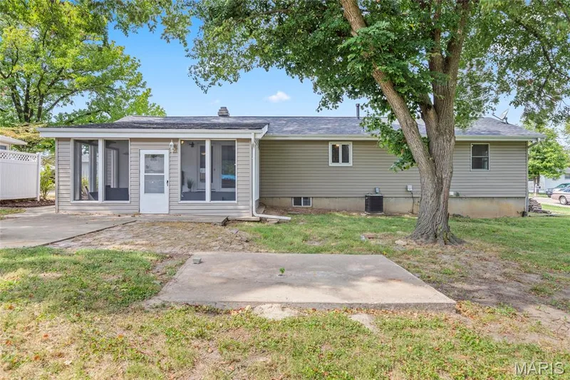 Rear exterior featuring a screened-in porch, light gray siding, and a concrete patio space — 712 Highland Drive, O'Fallon, MO 63366