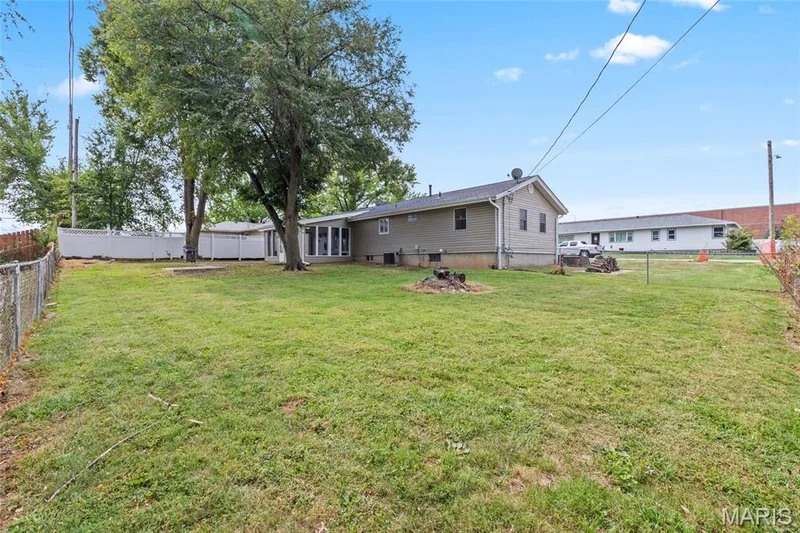 Expansive grassy yard with mature trees and a white privacy fence — 712 Highland Drive, O'Fallon, MO 63366