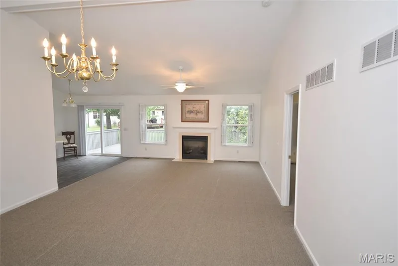 Vaulted ceiling, ceiling fan, fireplace with mantel, sliding glass door to exterior deck, and brass chandelier — 1129 Piepers Glen Lane #8A, O'Fallon, MO 63366