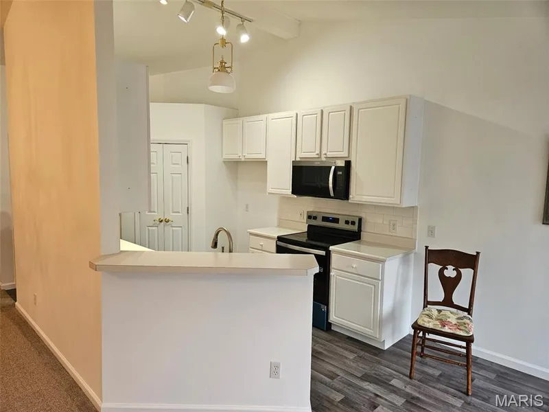 Kitchen featuring white cabinetry, black appliances, a subway tile backsplash, and wood-finish flooring — 1129 Piepers Glen Lane #8A, O'Fallon, MO 63366