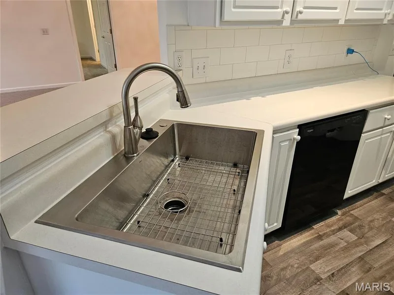 Stainless steel undermount sink with a gooseneck faucet, white subway tile backsplash, white cabinetry, and wood-finish flooring — 1129 Piepers Glen Lane #8A, O'Fallon, MO 63366