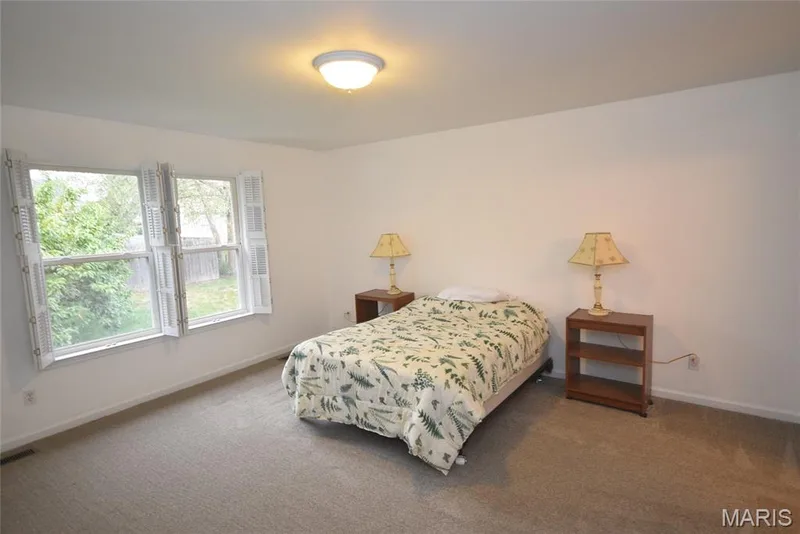 Neutral wall paint, carpeted flooring, two pane windows with white shutters, and a ceiling-mounted light fixture — 1129 Piepers Glen Lane #8A, O'Fallon, MO 63366