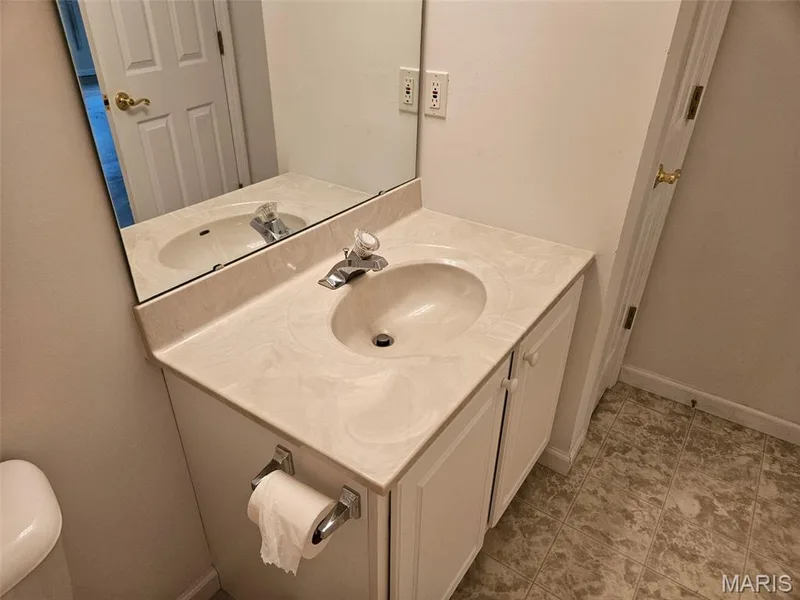 Vanity with integrated sink, chrome faucet, wall-mounted mirror, and cabinet storage — 1129 Piepers Glen Lane #8A, O'Fallon, MO 63366