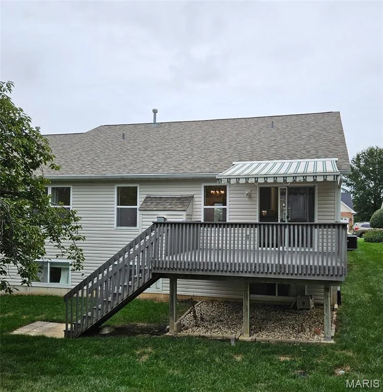 Rear exterior featuring a spacious wood deck, a striped retractable awning, and a sliding glass door — 1129 Piepers Glen Lane #8A, O'Fallon, MO 63366