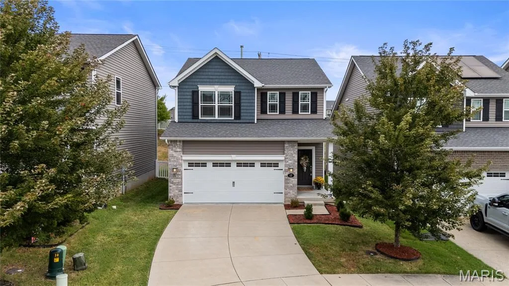 Two-story residence featuring a two-car garage, stone and siding exterior, and a concrete driveway — 17 Rydal Place, St Charles, MO 63303
