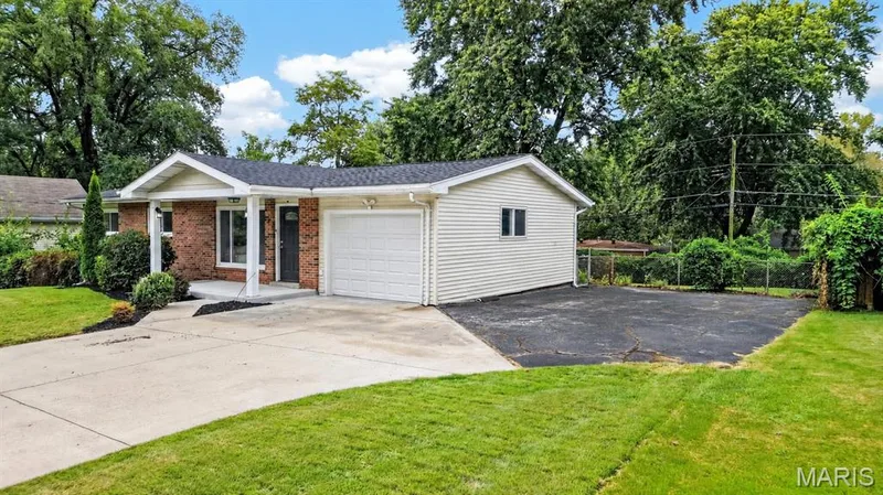 Attached one-car garage, concrete driveway, and separate side parking pad — 34 Highland Drive, St Charles, MO 63303