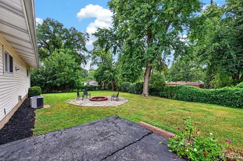 Backyard with a gravel fire pit area and mature shade trees — 34 Highland Drive, St Charles, MO 63303