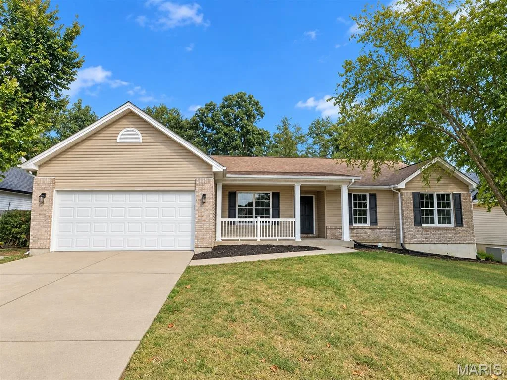 Front elevation featuring a covered porch, brick and siding exterior, attached garage, concrete driveway, and mature landscaping — 1731 Fairview Farms Circle, Wentzville, MO 63385
