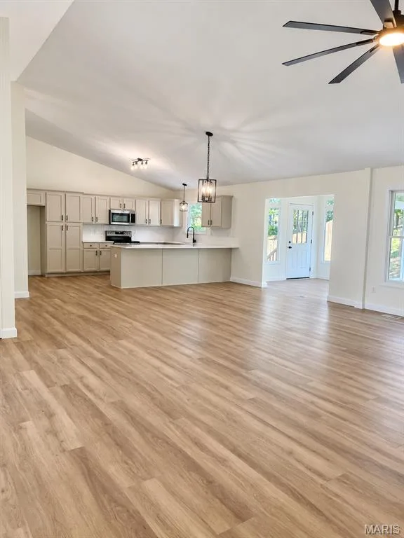 Open-concept living area featuring wood-finish flooring, vaulted ceilings, and recessed lighting — 1731 Fairview Farms Circle, Wentzville, MO 63385